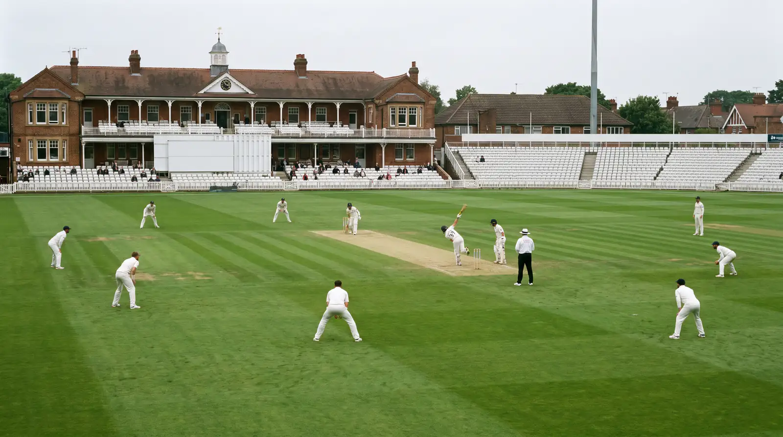 County Championship four-day cricket match in progress at an English ground with sparse mid-week attendance behind the boundary