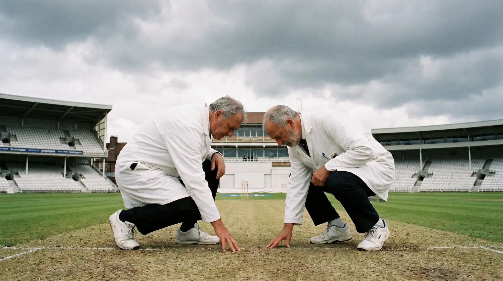 Cricket umpires inspect a county pitch under threatening English clouds