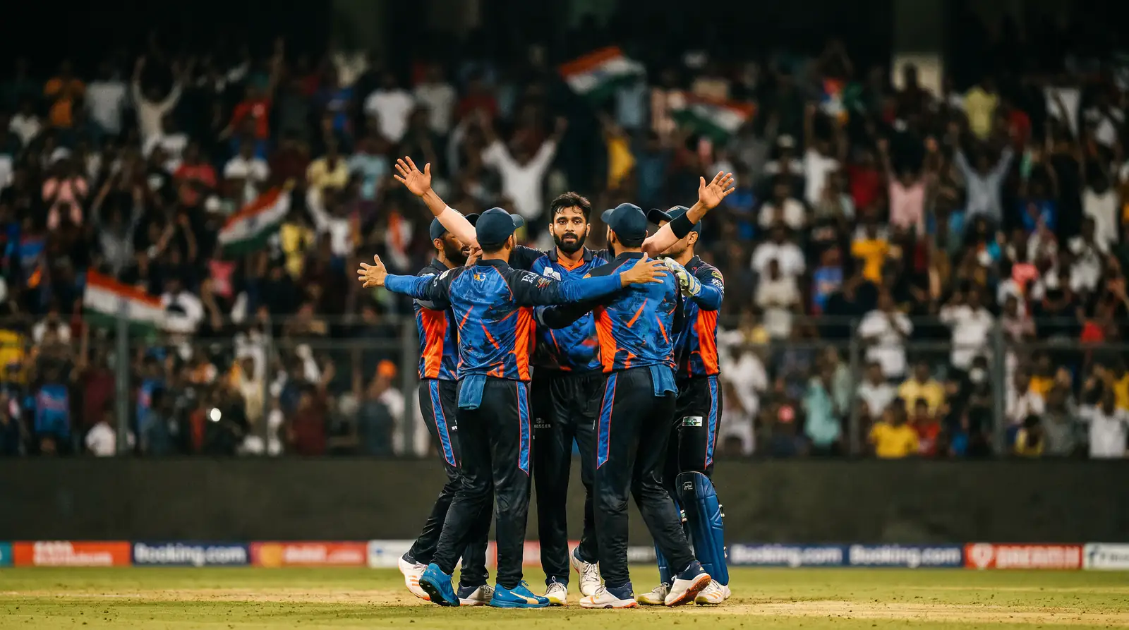 Franchise cricket team celebrating a wicket on the boundary during a T20 league fixture under floodlights