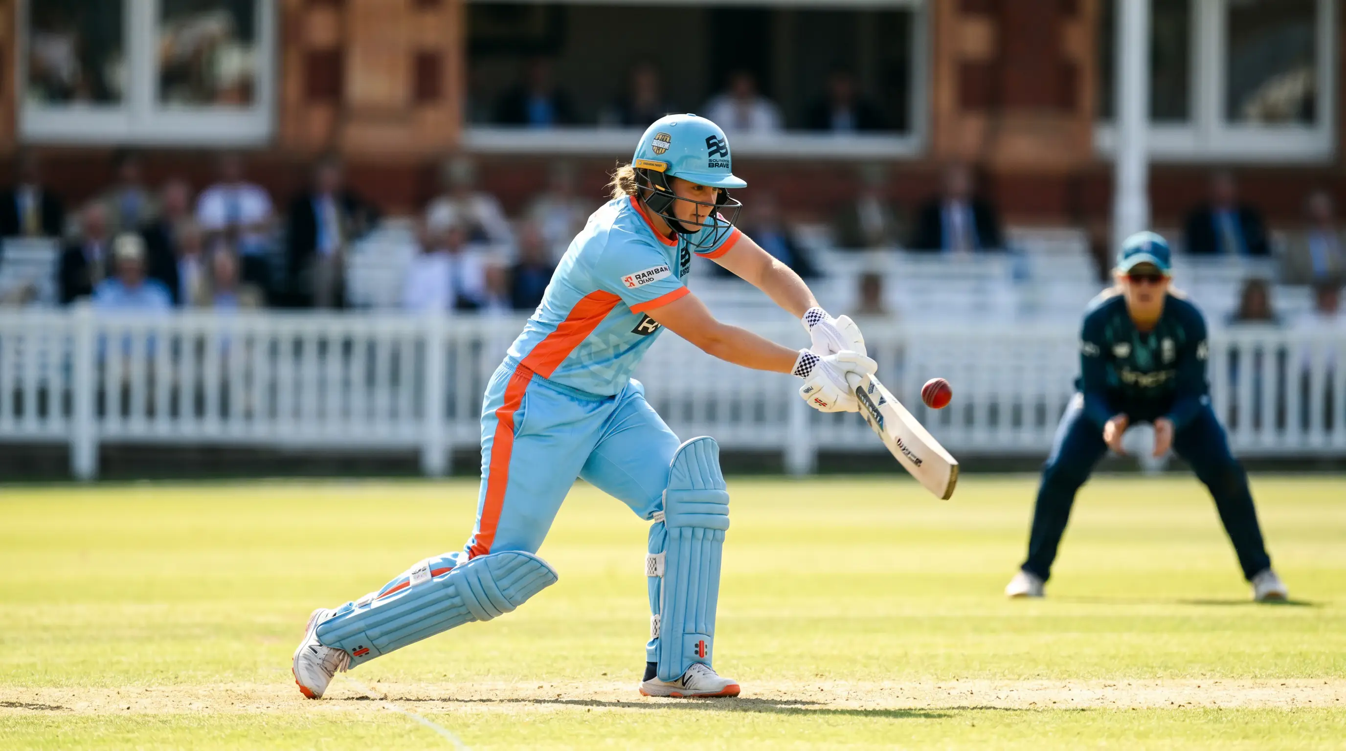Female cricket batter plays a controlled drive on a sunlit ground in the powerplay